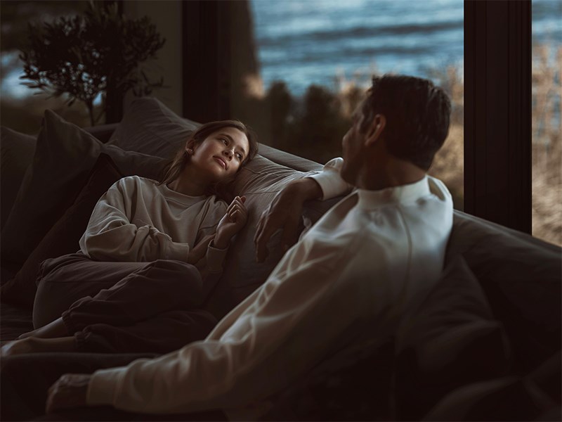 Varm och dunkel inomhusmiljö, far och dotter umgås i soffan
